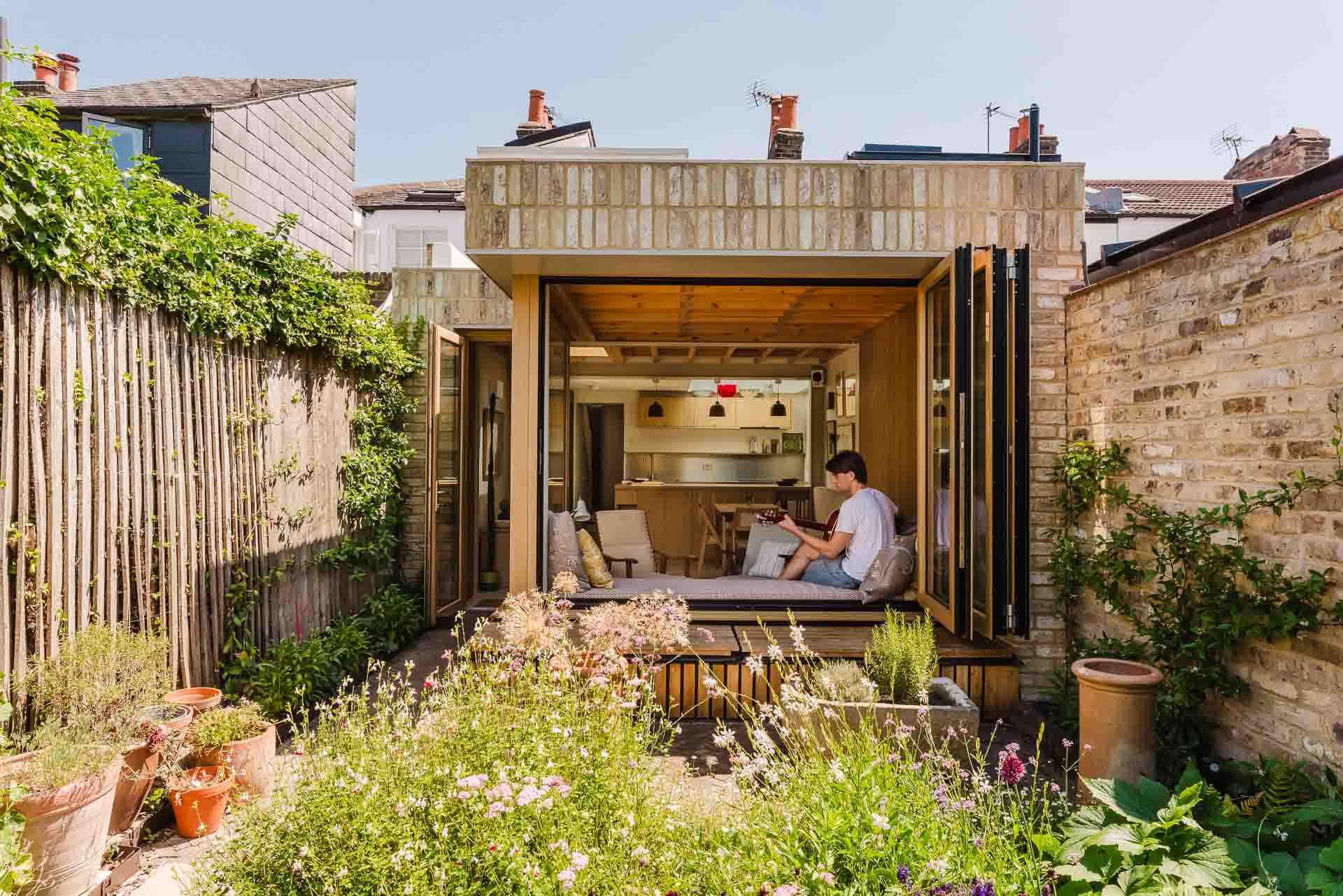 Modern brick house extension with bi-fold doors open to a lush garden patio.