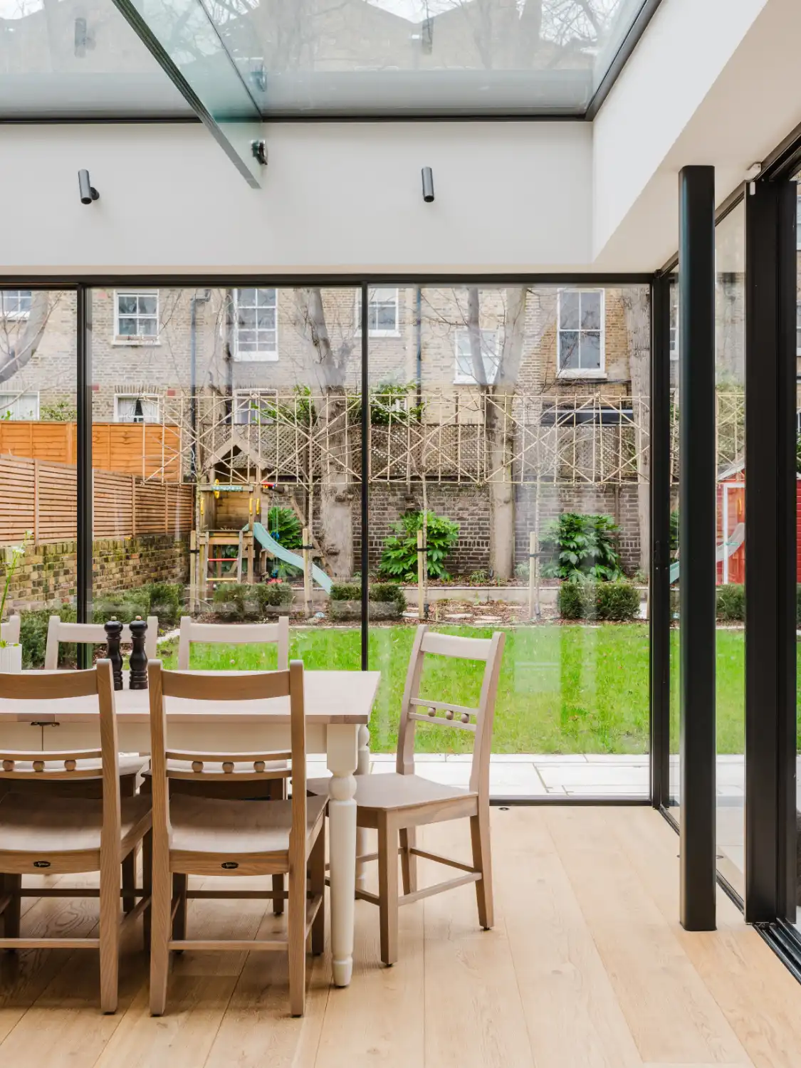 Natural light interior photography of a kitchen extension and dining area overlooking the garden in a restored Westminster home, London.